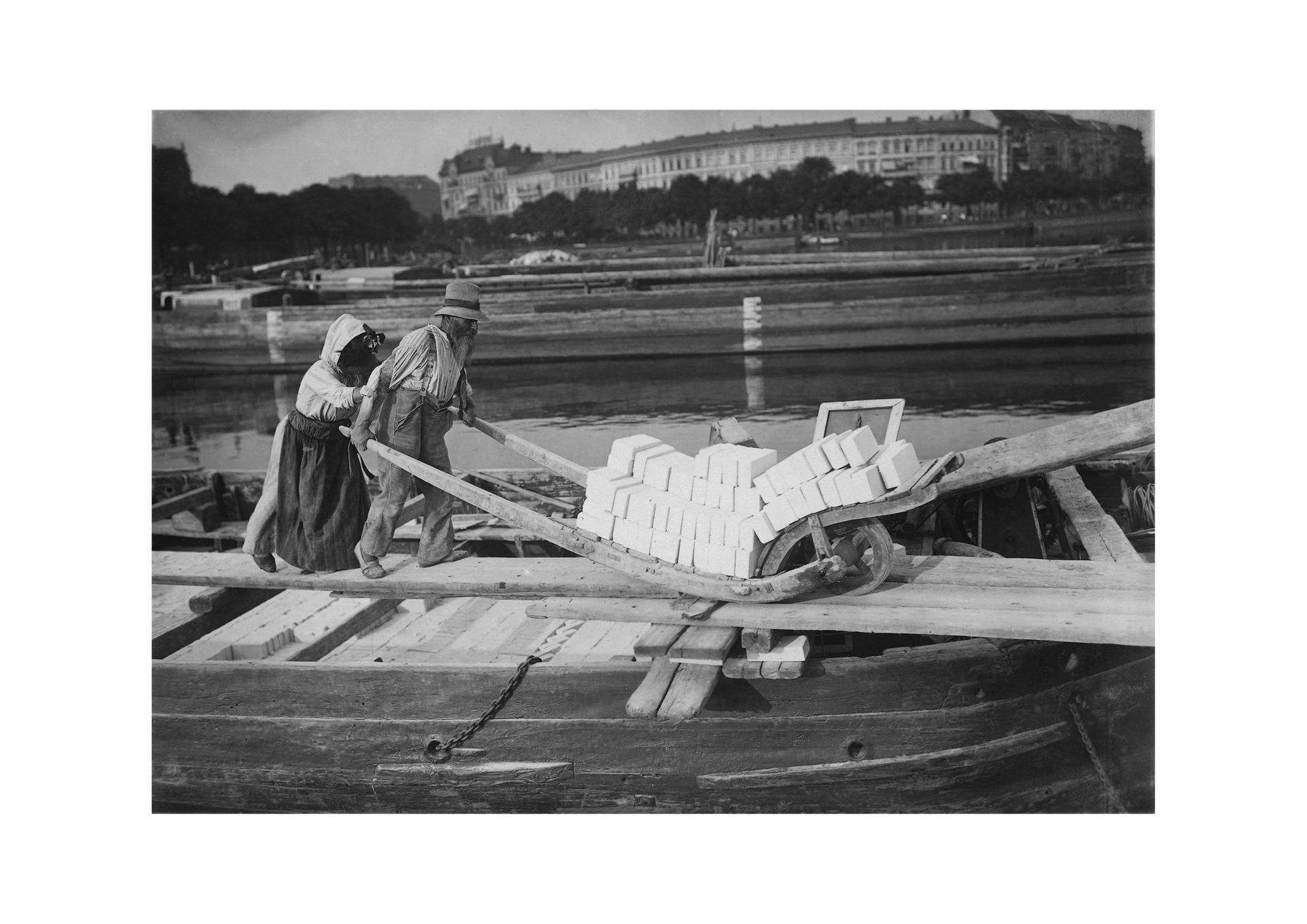Die Ziegel für den Aufbau Berlins kamen per Kahn aus Brandenburg. Ein altes Paar lädt 1910 an der Spree einen Kahn aus.
