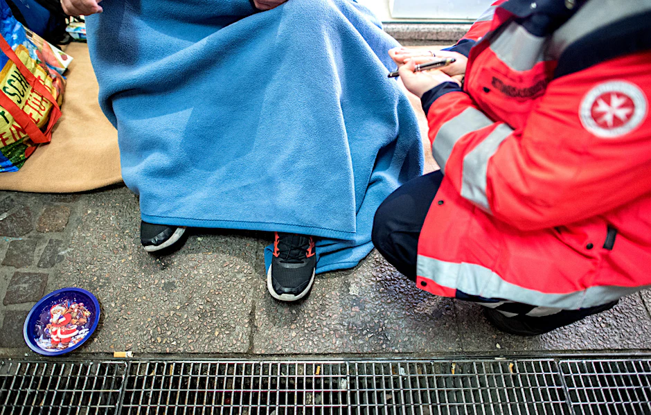 Eine ehrenamtliche Helferin der Johanniter spricht in der Innenstadt mit einem Obdachlosen. 