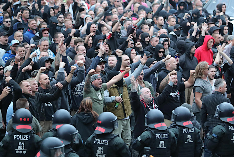 Polizisten stehen in der Innenstadt am Karl-Marx-Monument bei einer Kundgebung der rechten Szene.