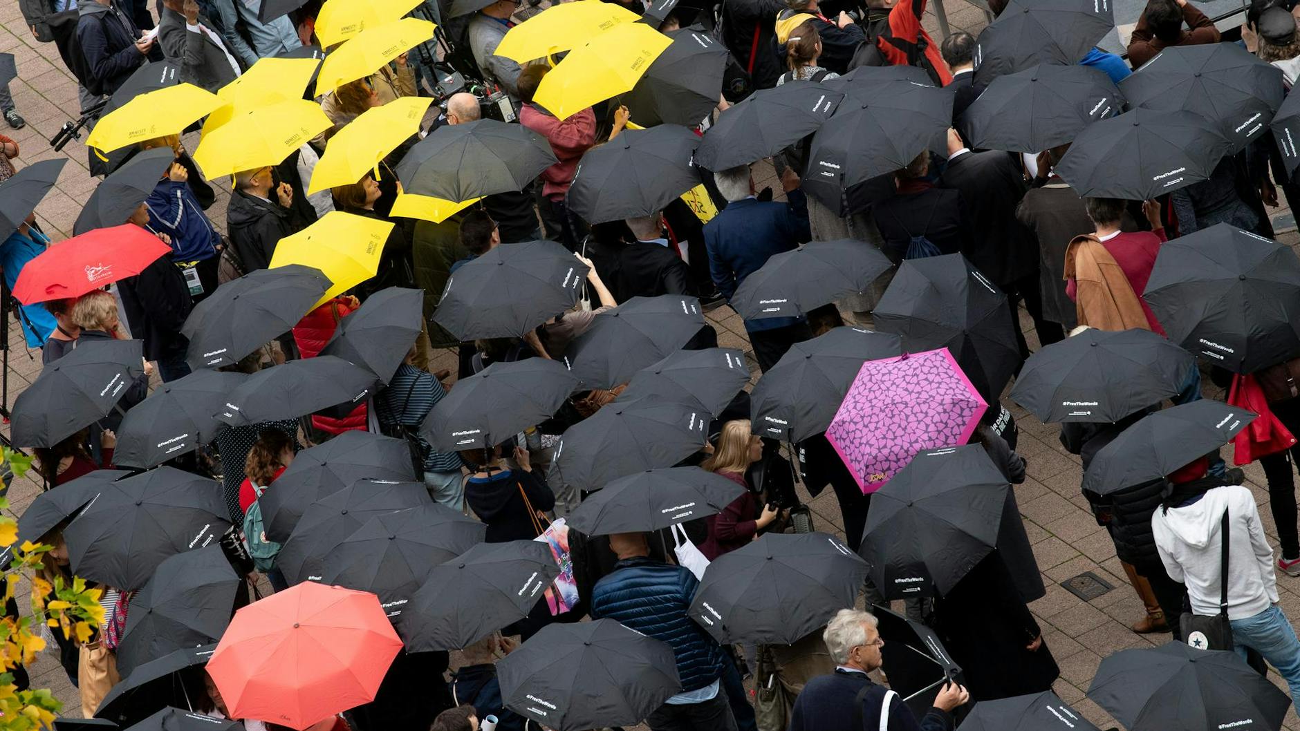 Mit Regenschirmen beteiligen sich zahlreiche Menschen auf der Buchmesse an einer Mahnwache für die Meinungsfreiheit. Dabei ging es in erster Linie um ein Zeichen der Solidarität für den in China inhaftierten Autor Gui Minhai.