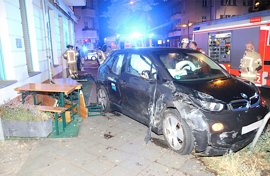 Feuerwehrleute inspizieren das verunglückte Carsharing-Auto vor der Kneipe.