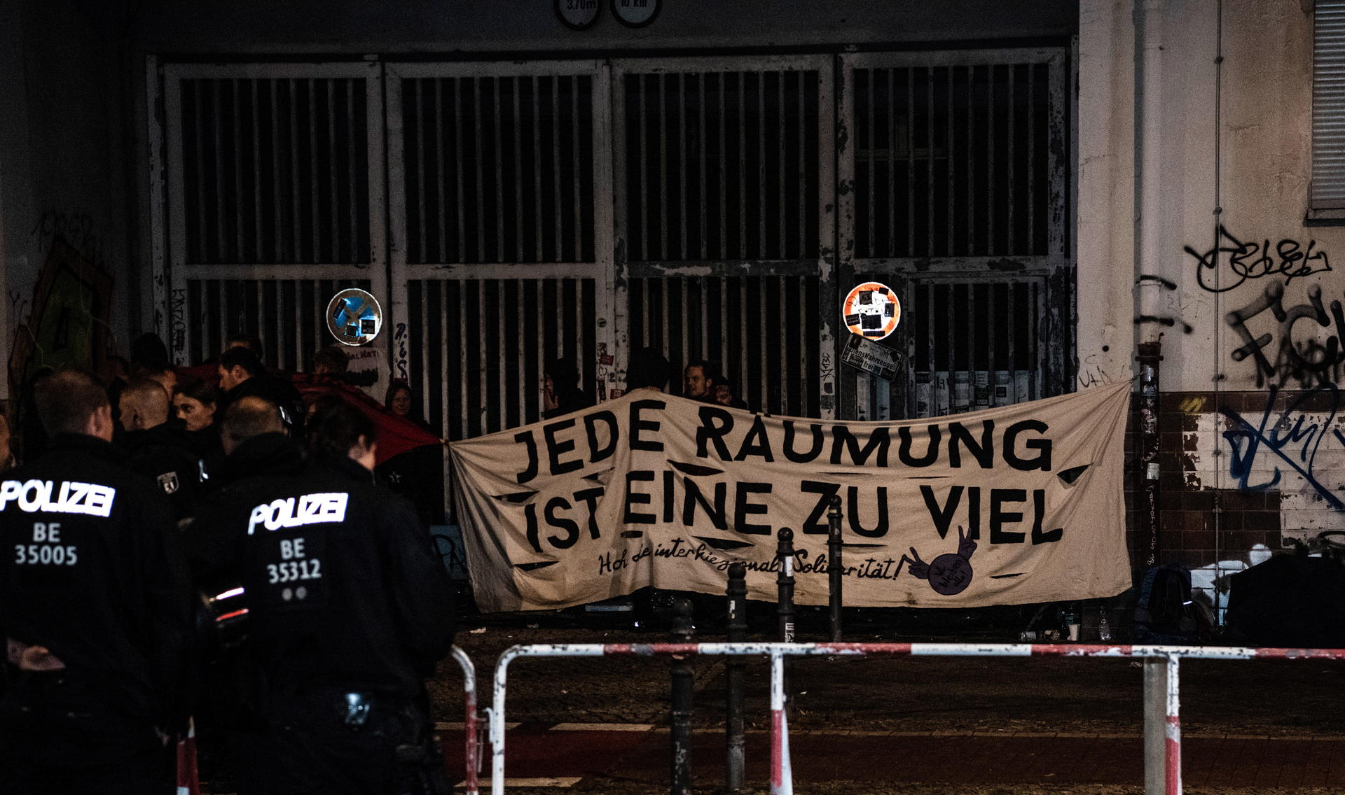 Demonstranten mit einem Transparent stehen am späten Sonnabend vor einem besetzten Haus an der Frankfurter Allee. Dort fand eine sogenannte Solidaritätskundgebung für die Besetzer statt.
