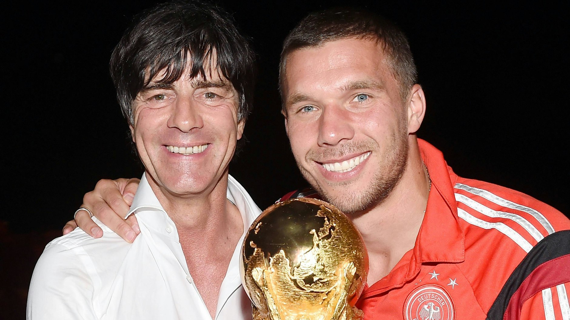Lukas Podolski und Jogi Löw mit dem Weltmeisterpokal.