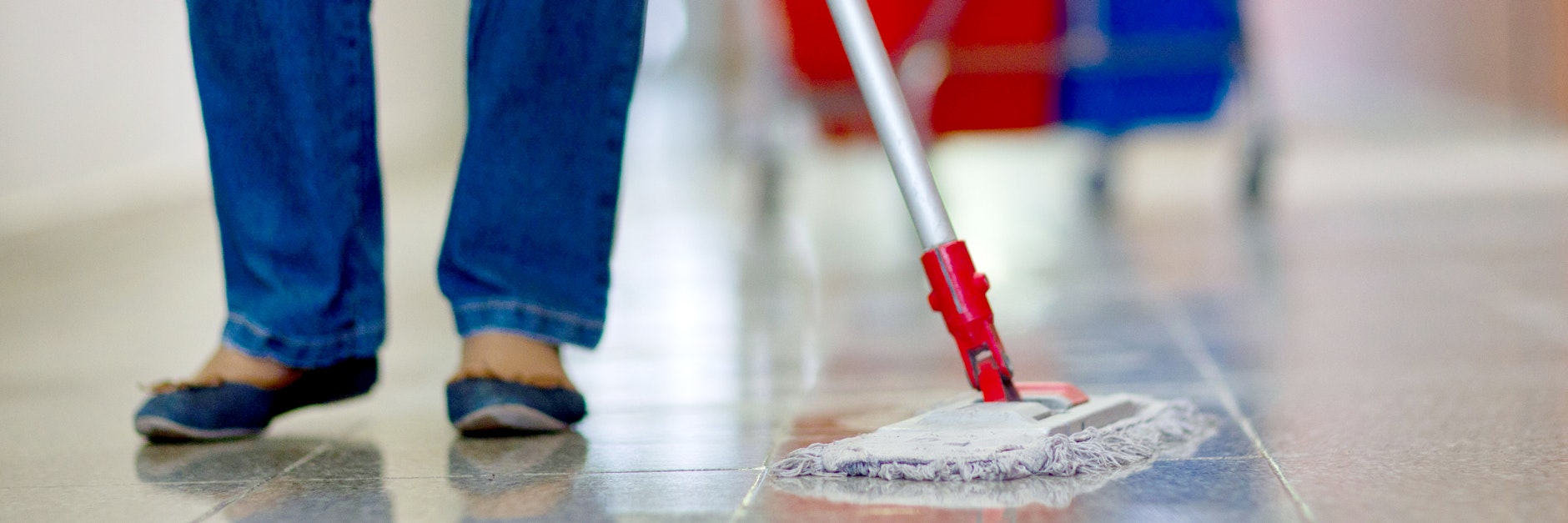Eine Gebäudereinigerin wischt einen Flur.