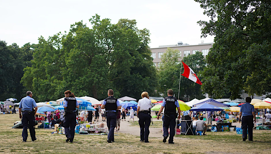 olizisten gehen über den bisherigen, provisorisch errichteten „Thaipark“.