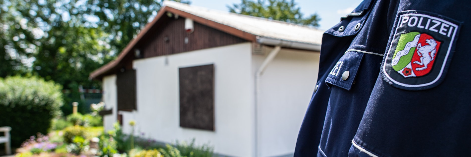 Ein Polizist steht vor einer Gartenlaube in Münster. Hier wurde sexueller Missbrauch an Kindern aufgedeckt