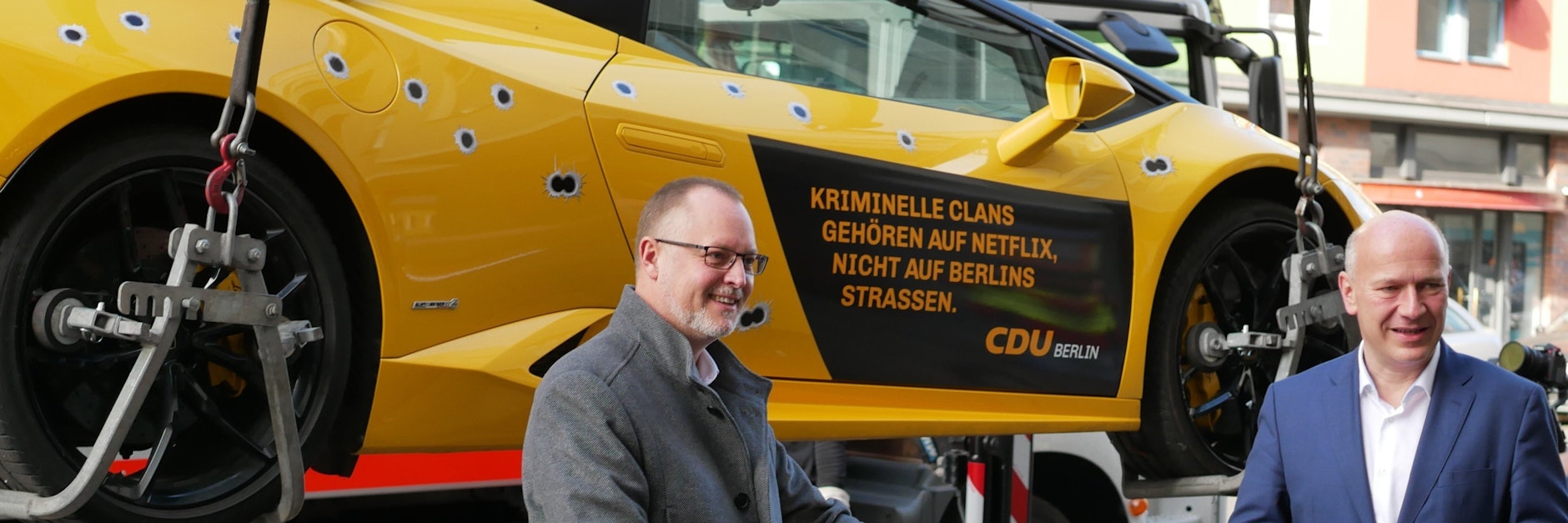 Kai Wegner, CDU-Landeschef (r), und Falko Liecke (CDU, Neuköllns Gesundheitsstadtrat, stehen vor einem gemieteten Lamborghini mit aufgeklebten Einschusslöchern. 