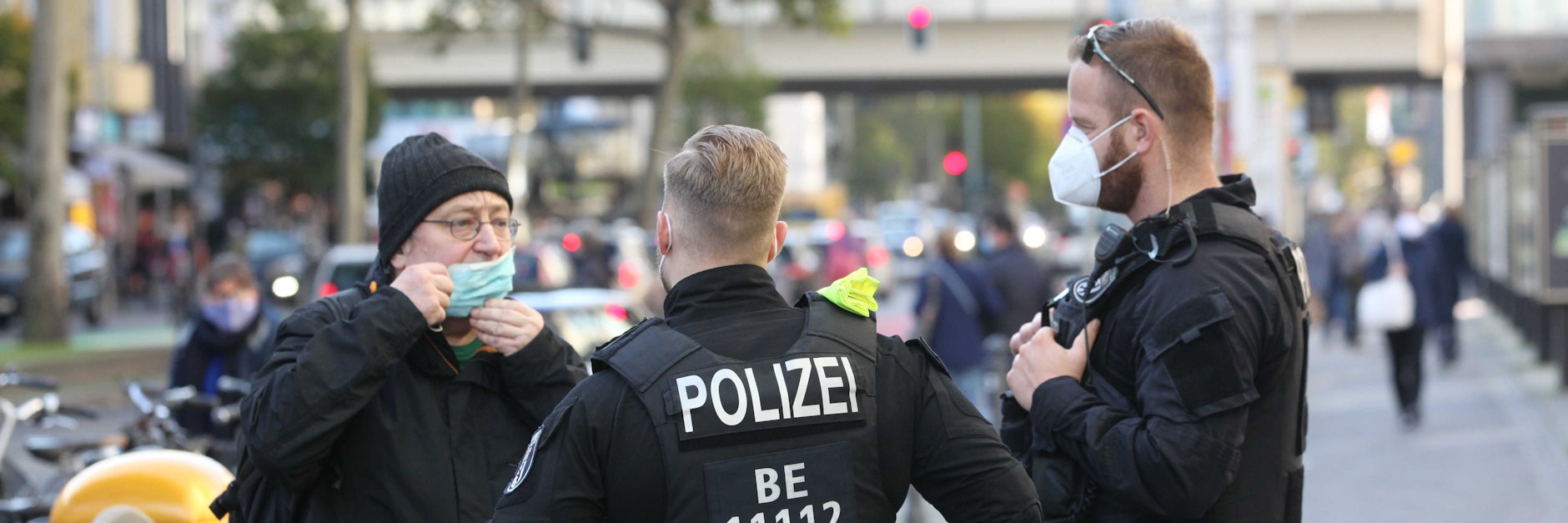 Zwei Polizisten kontrollieren in der Steglitzer Schlossstraße bei einem Mann die Maskenpflicht.