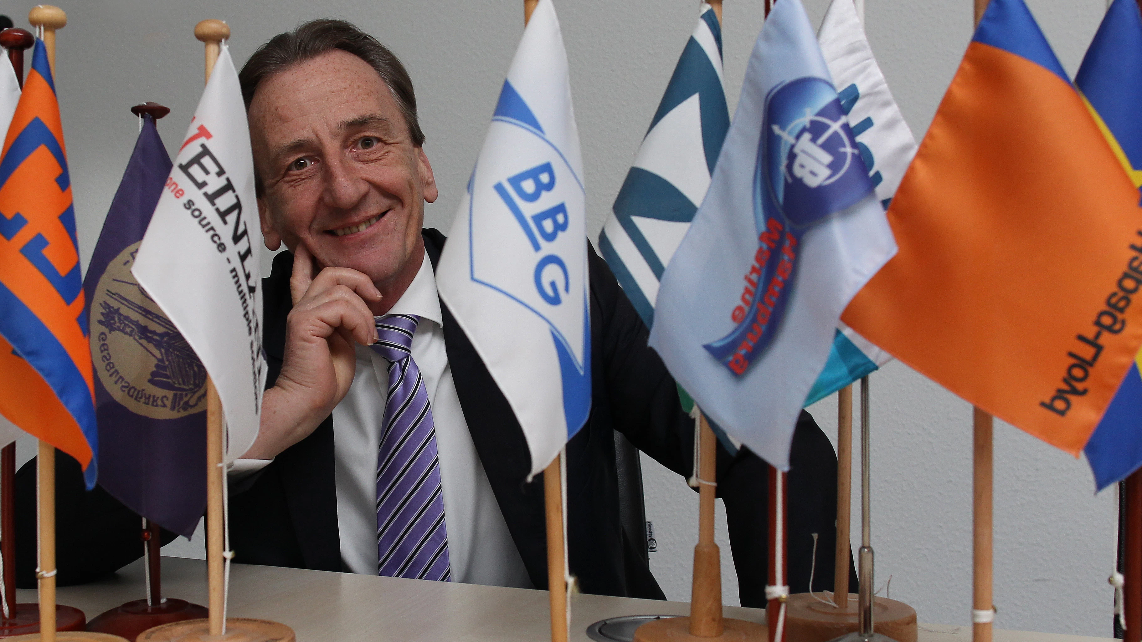 Gerald Rynkowski mit Flaggen der vielen Reedereien weltweit, mit denen sein Unternehmen zusammenarbeitet.