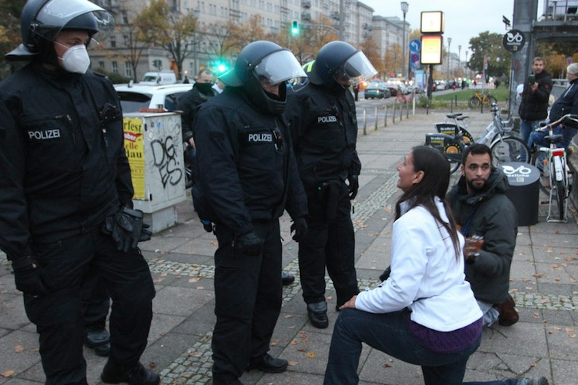 Eine Demonstrantin kniet vor Polizisten nieder und redet sie auf sie ein.
