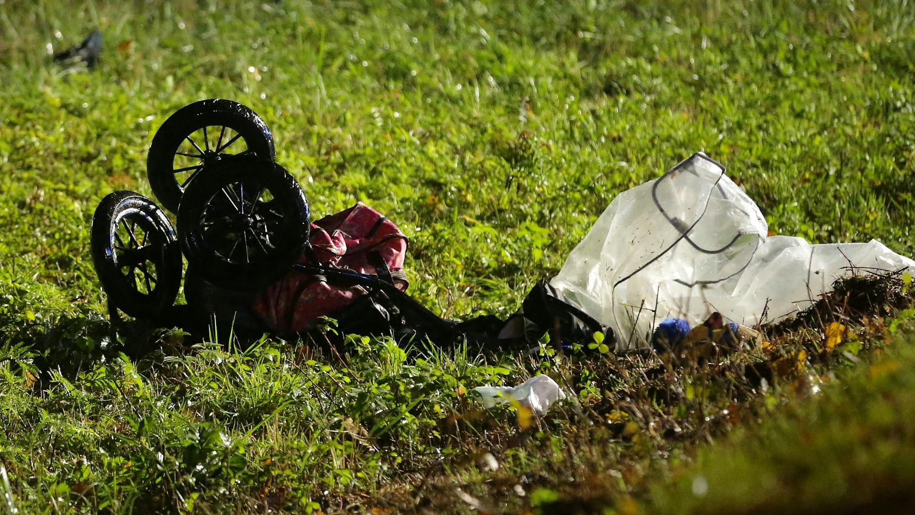 Ein zerstörter Kinderwagen liegt nach dem Unfall auf der Wiese. 