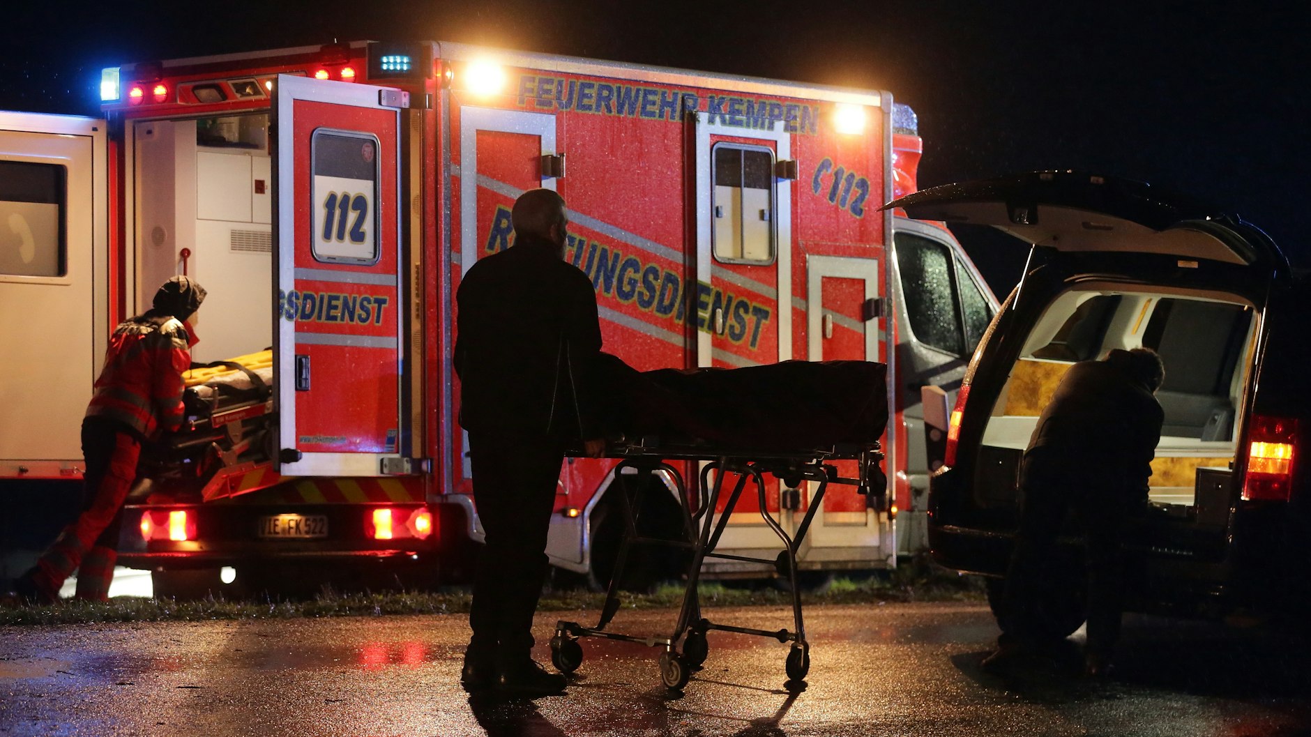 Bestatter verladen das Unfallopfer in einen Leichenwagen. 