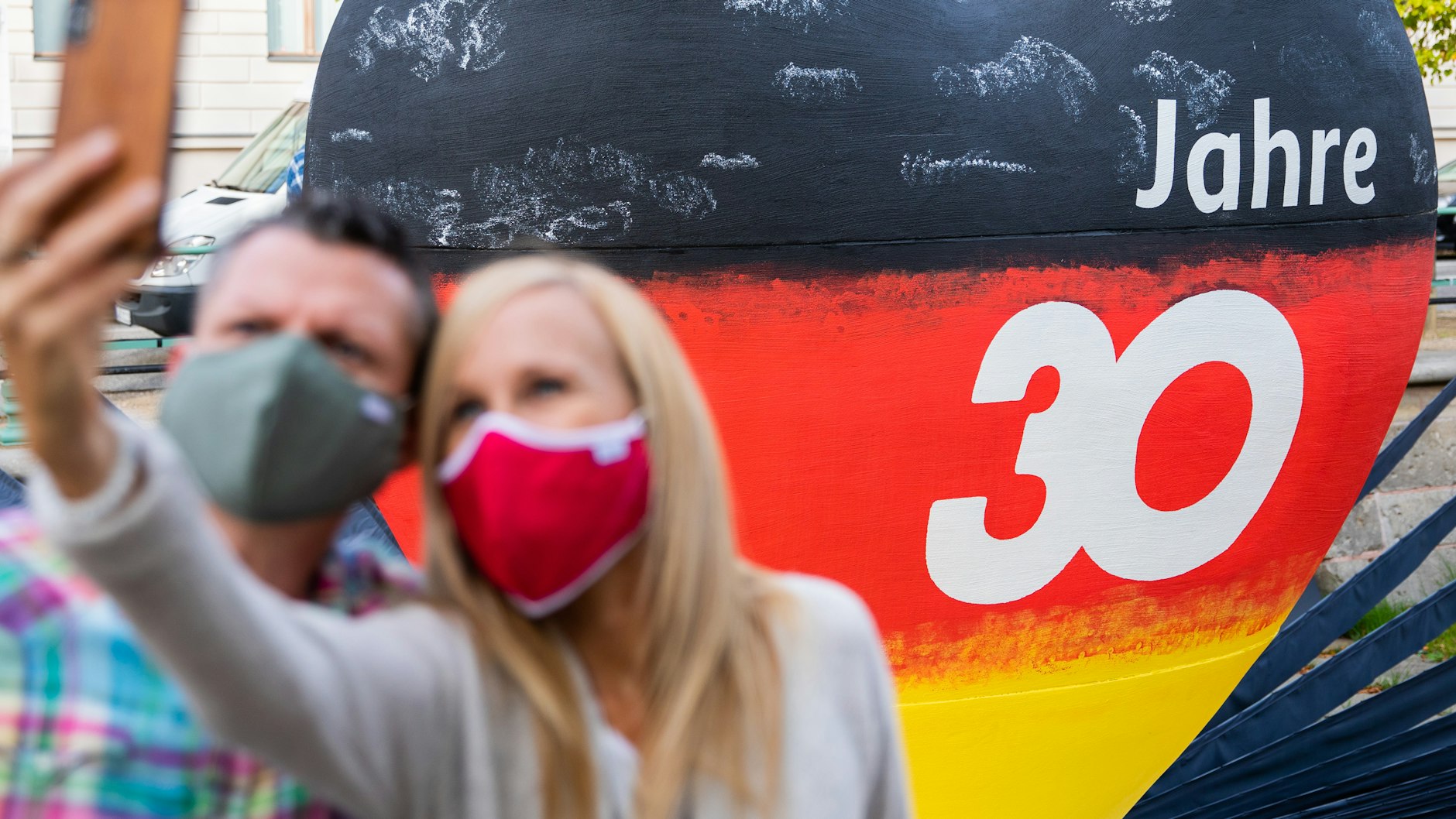 Ein Pärchen fotografiert sich in Potsdam&nbsp;vor einem schwarz-rot-goldenen Herz mit der Aufschrift „30 Jahre“.