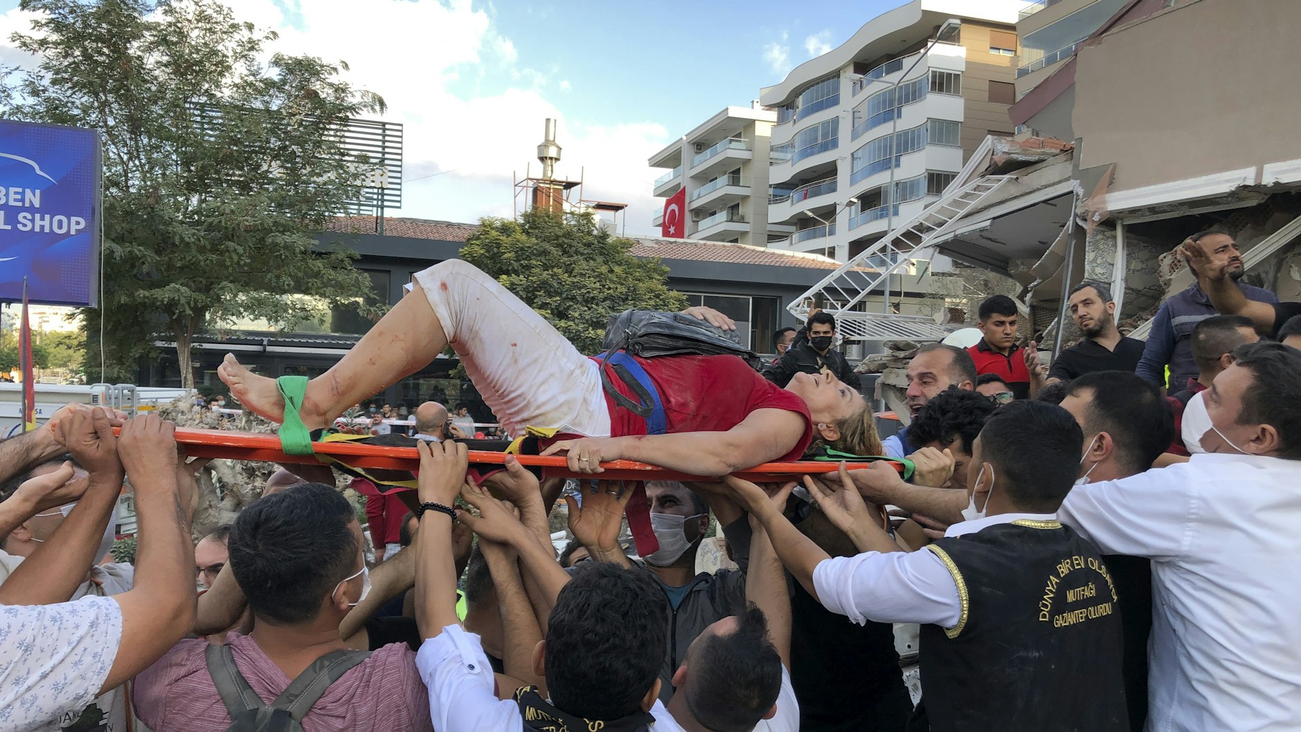 Türkei, Izmir: Rettungskräfte und Anwohner tragen eine verletzte Frau, die in den Trümmern eines eingestürzten Gebäudes gefunden wurde.