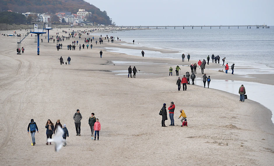 Spaziergänger sind bei grauem Herbstwetter am Ostseestrand in Heringsdorf unterwegs.