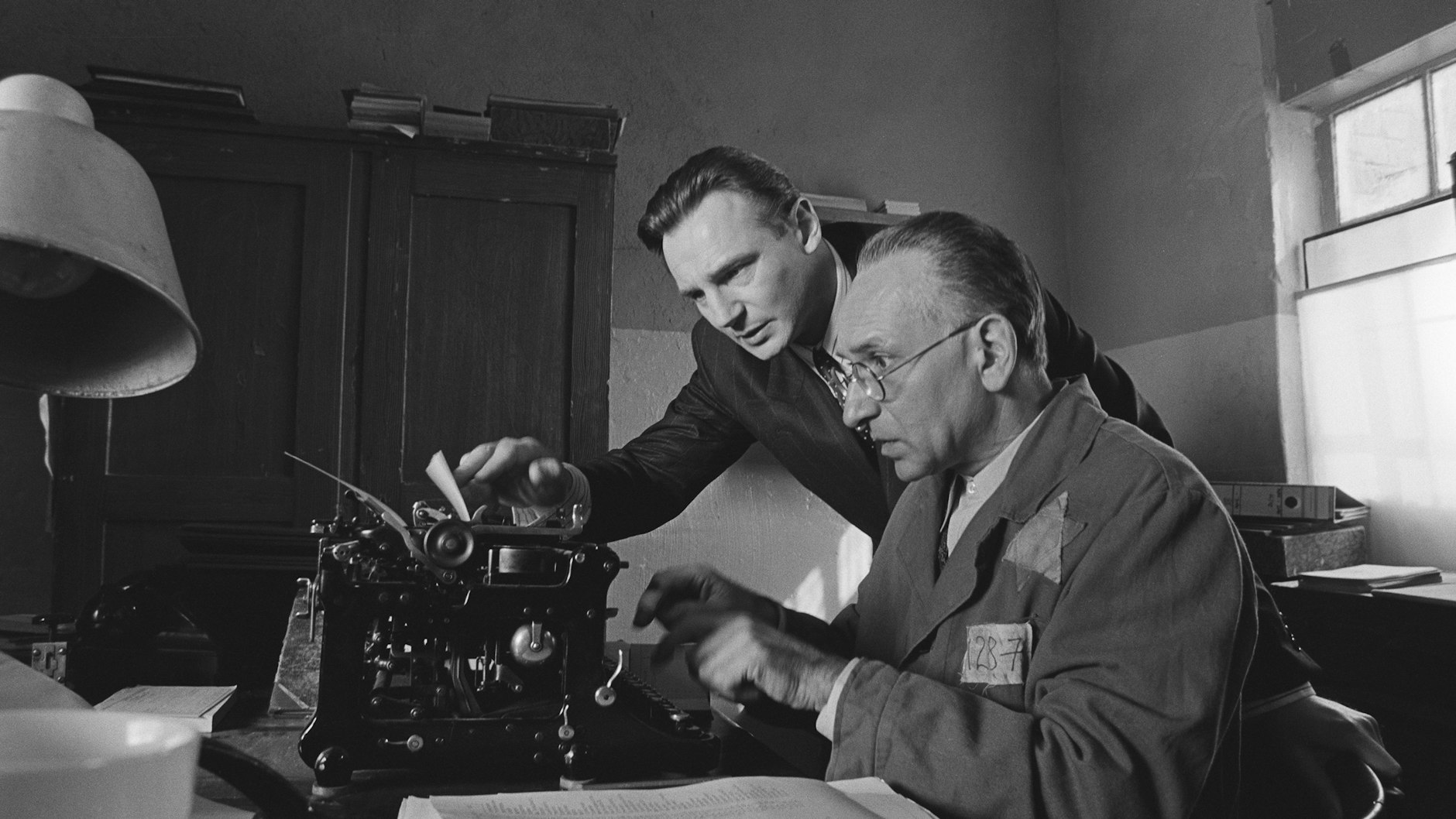 Oskar Schindler (Liam Neeson, l.) und sein jüdischer Buchhalter Itzhak Stern (Ben Kingsley) stellen eine Liste von über 1100 jüdischen Arbeitern zusammen, die Schindler zu retten hofft – eine Szene aus dem Film „Schindlers Liste“.