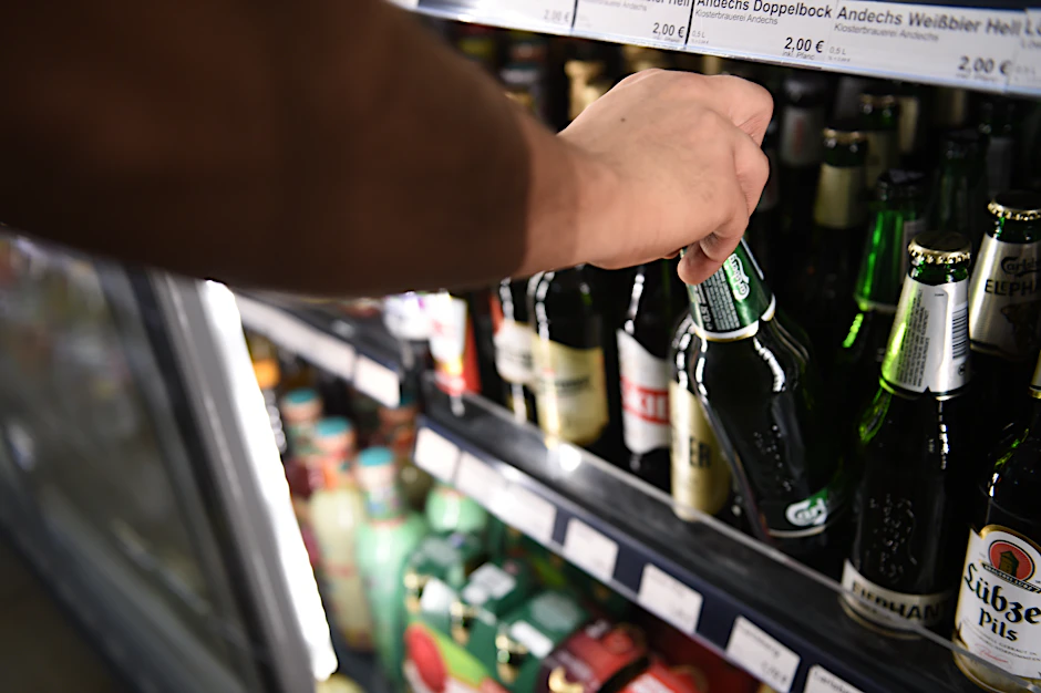 Ein Mann holt eine Flasche Bier aus einem Kühlschrank in einem Spätkauf in Berlin-Mitte.