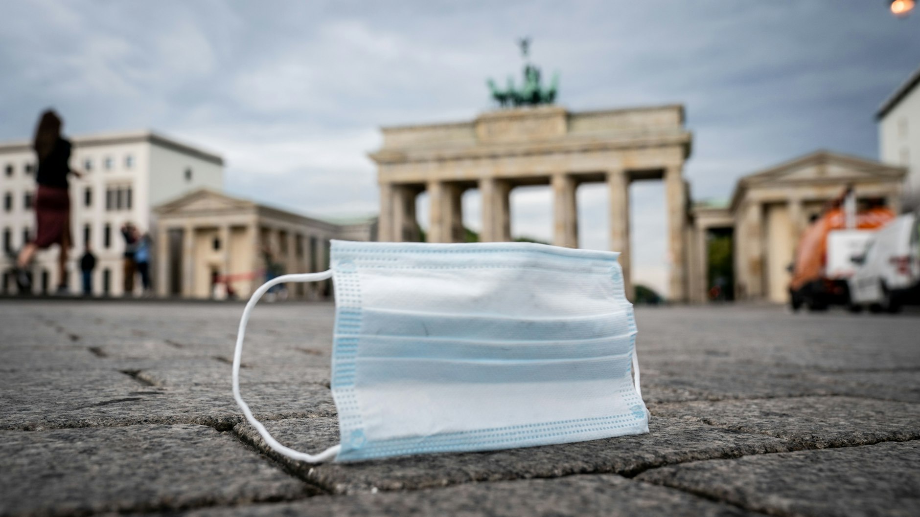 Ein Mund-Nasen-Schutz wird vom Wind über den Pariser Platz vor dem Brandenburger Tor geweht. Erneut liegt die Zahl der neuen Corona-Infektionen in Deutschland über der Schwelle von 2000.
