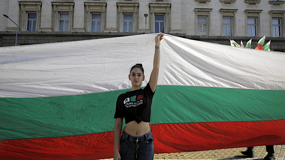 Eine junge Frau protestiert vor einer riesigen bulgarischen Fahne gegen die Regierung in Sofia.