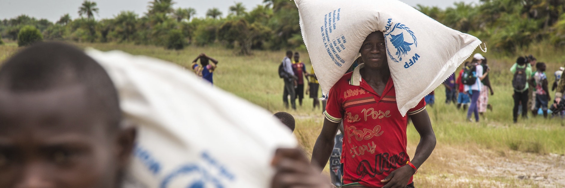 Junge Männer in Sierra Leone schleppen Getreidesäcke&nbsp; - Hungerhilfe des Welternährungsprogramms, abgeworfen von einem Hubschrauber.&nbsp;&nbsp;