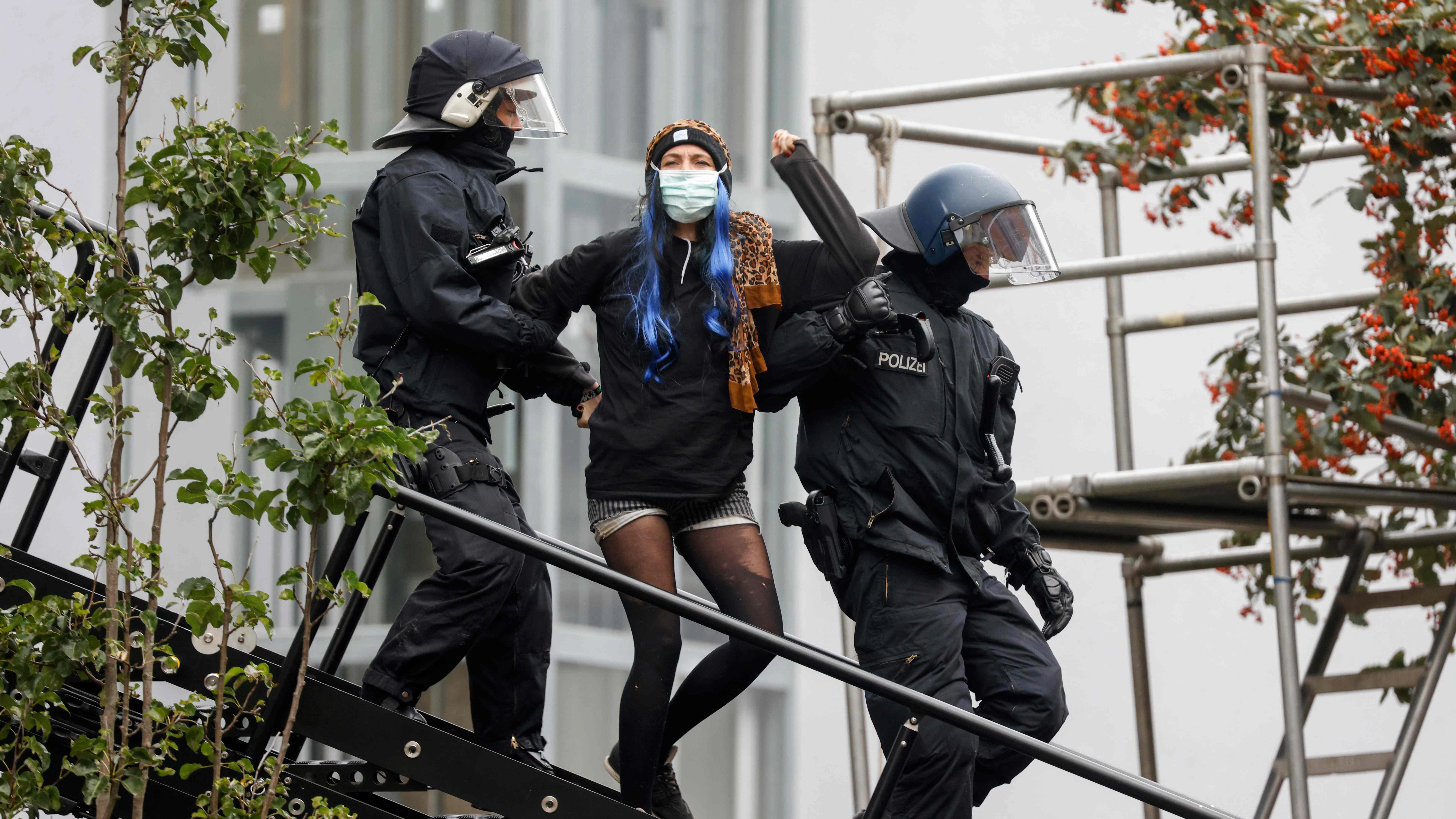 Eine Frau wird von Polizisten aus dem Haus geführt.&nbsp;
