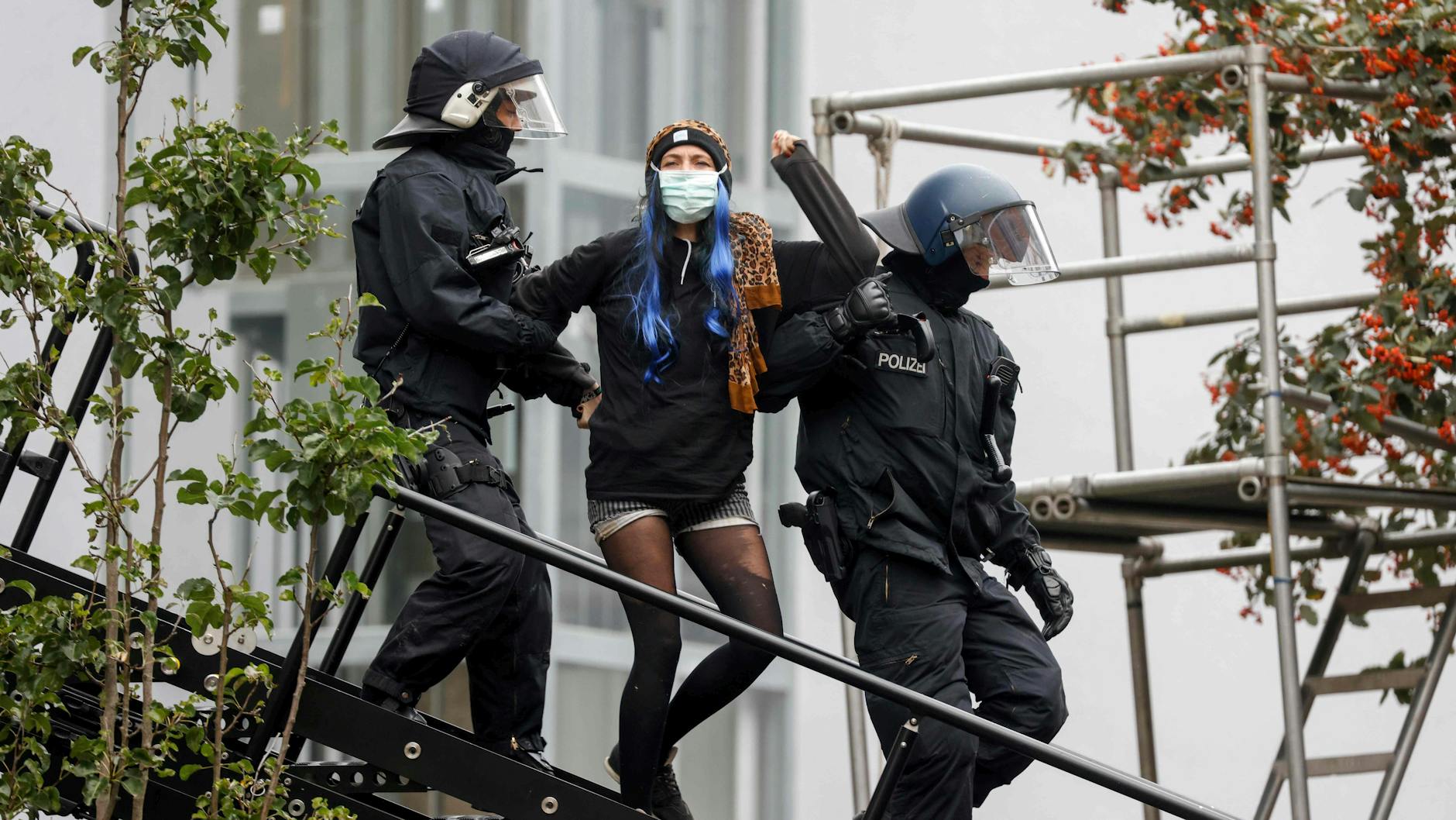 Polizisten führen eine der Bewohnerinnen aus dem Haus.
