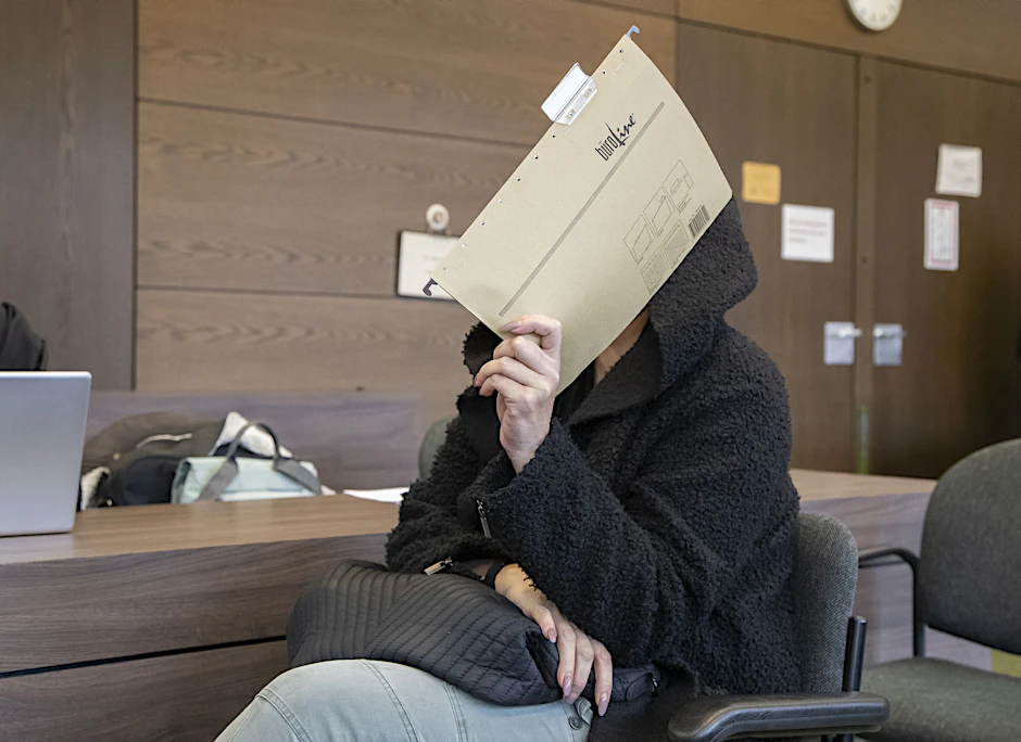 Die Angeklagte sitzt vor Gericht und verdeckt ihr Gesicht.