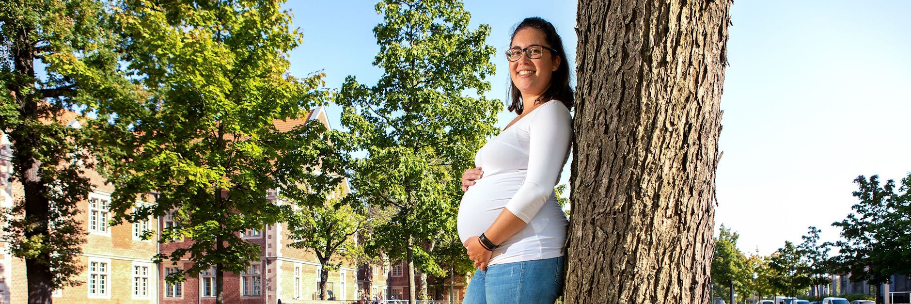 Anna B. lehnt an einen Baum im Klinikpark. In zwei Monaten erwartet sie ihr erstes Kind, obwohl sie vor zwei Jahren schwer krank war.
