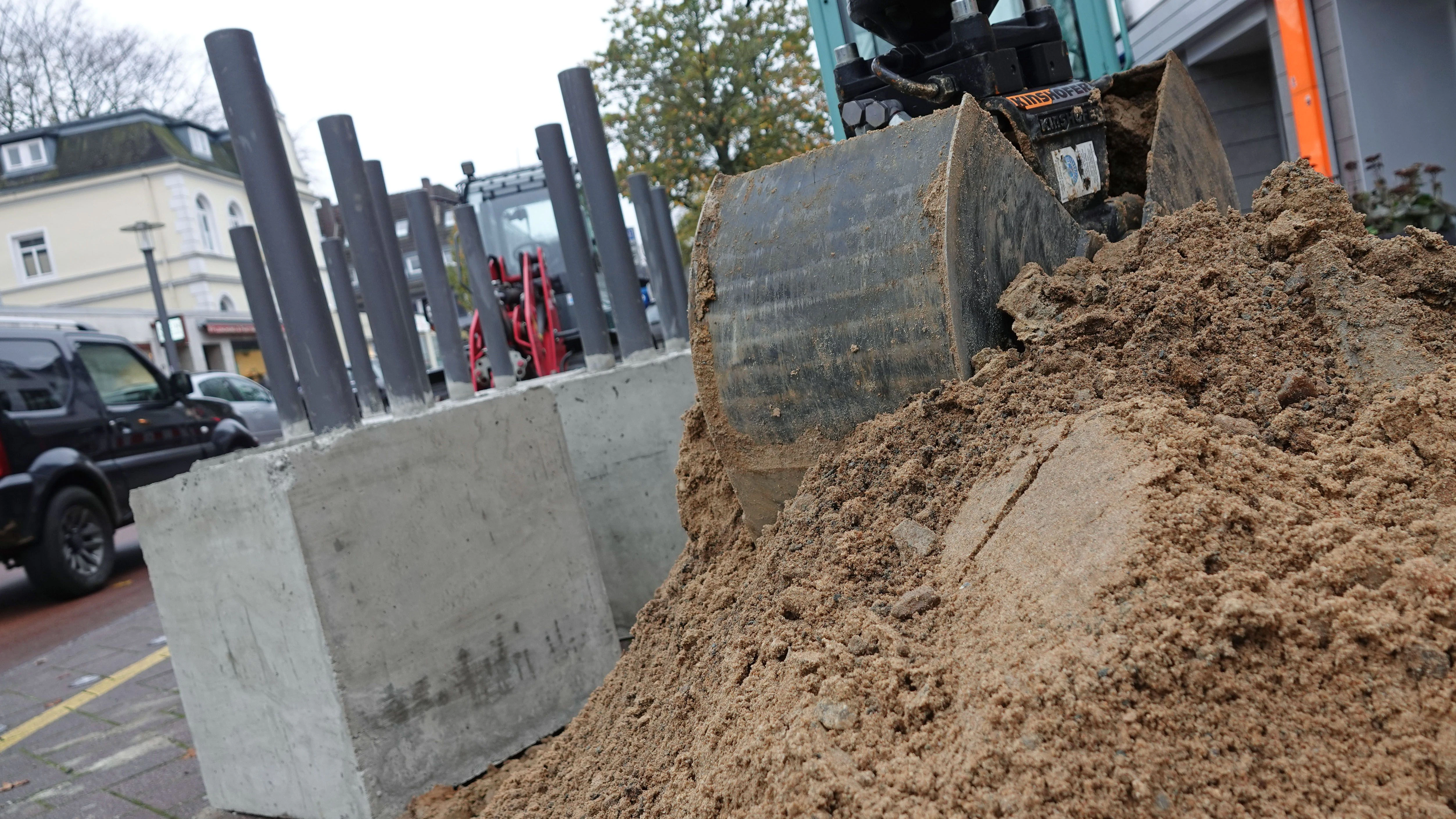 Vollstahlpoller stehen neben einem Sandhaufen an der Hamburger Waitzstraße. In der von zahlreichen Schaufenster-Unfällen geplagten Straße sollen sie die Geschäfte schützen.