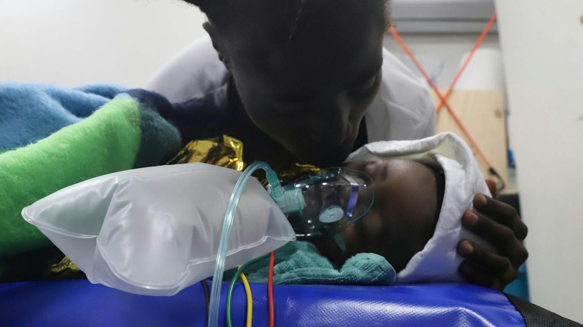 An Bord des Schiffes der Organisation Open Arms küsst eine Frau ihr Kind, das nach der Rettung aus dem Mittelmeer beatmet wird.