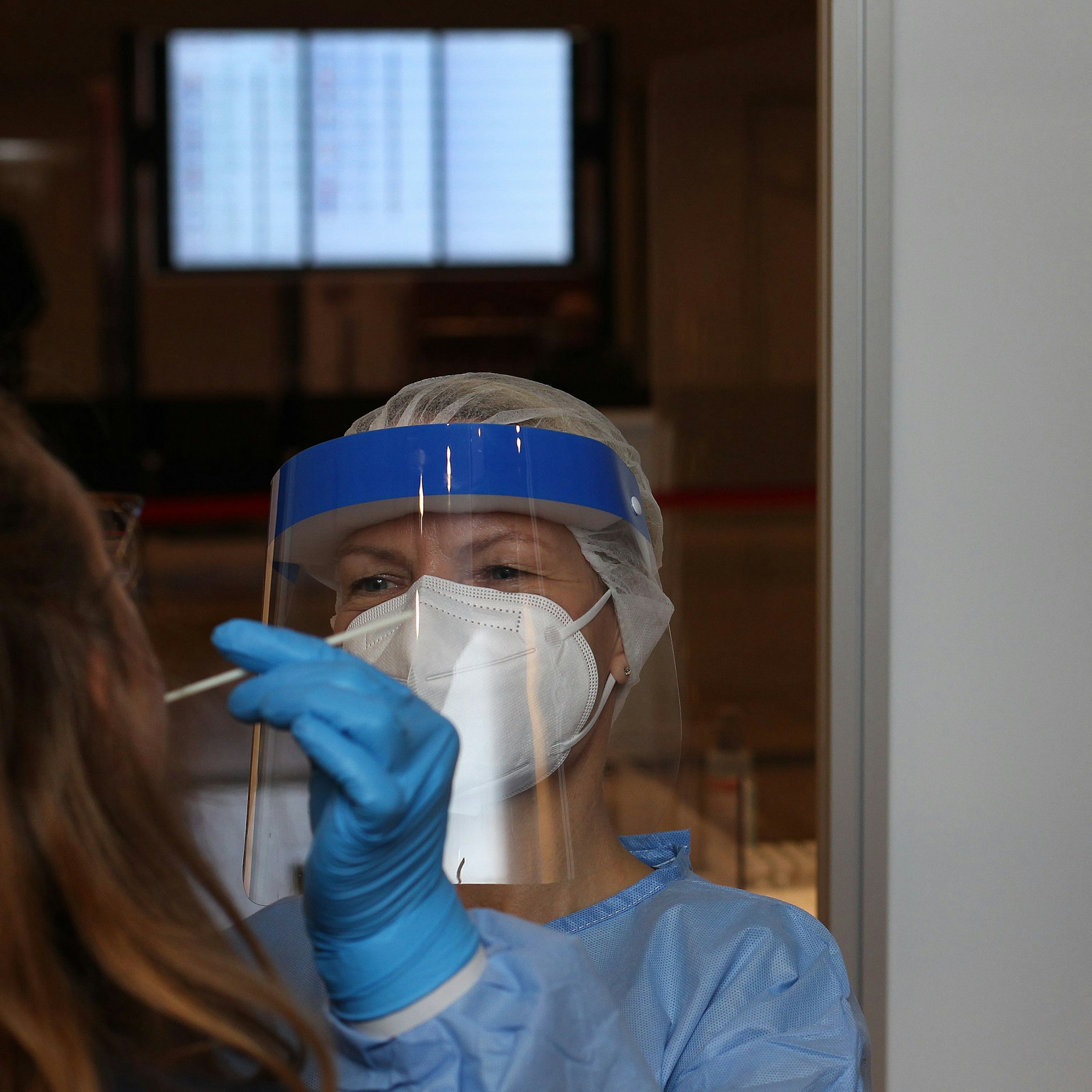 Von Wiebke sehen Kunden bei Corona-Test nur die freundlichen Augen. Im Hintergrund die Abflug- und Ankunfts-LEDs im Terminal 1 des BER.<br>