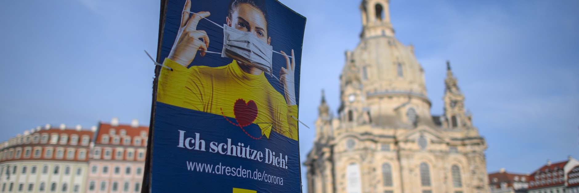 Ein Plakat weist vor der Dresdener Frauenkirche auf die Nutzung von Mund-Nasen-Masken hin.&nbsp;