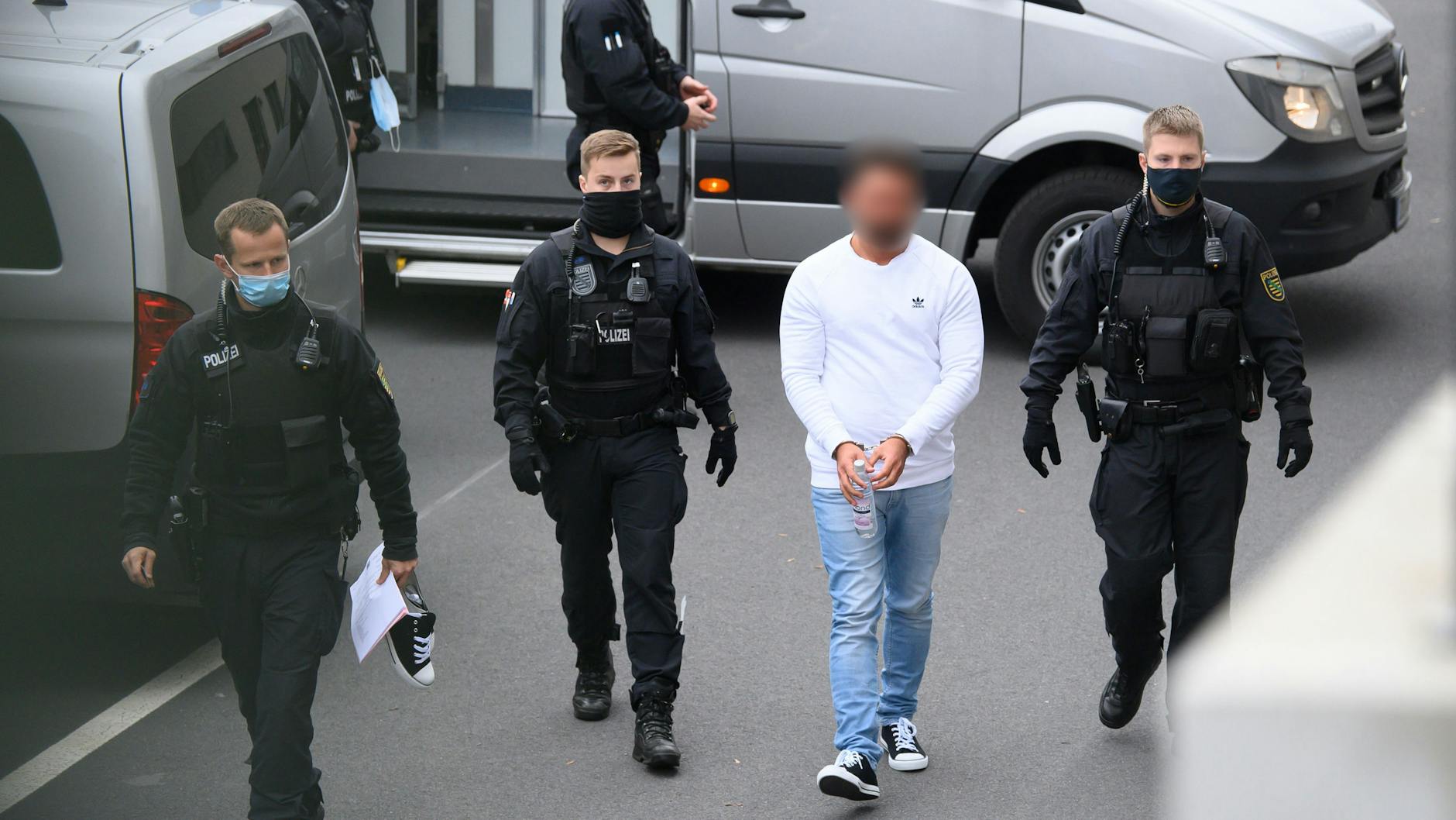 Ein Tatverdächtiger wird am Dienstag von Polizisten in das Gebäude des Oberlandesgerichts in Dresden geführt. 