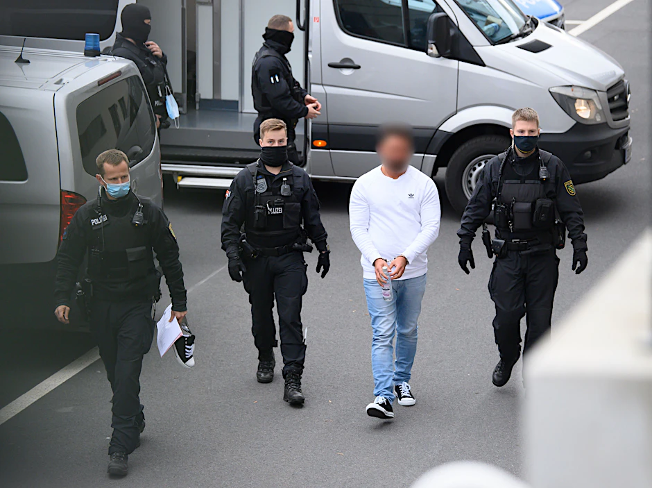 Eines der drei verhafteten Clan-Mitglieder wird am Dienstag von Polizisten in das Gebäude des Oberlandesgerichts in Dresden geführt.