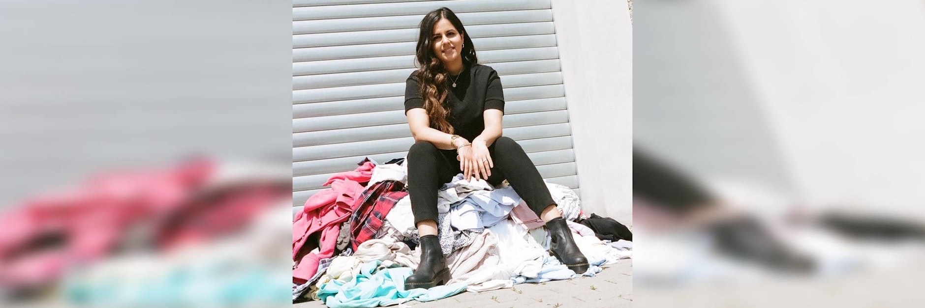 Chemie-Ingenieurin Alina Bassi auf einem Berg von Kleidung.