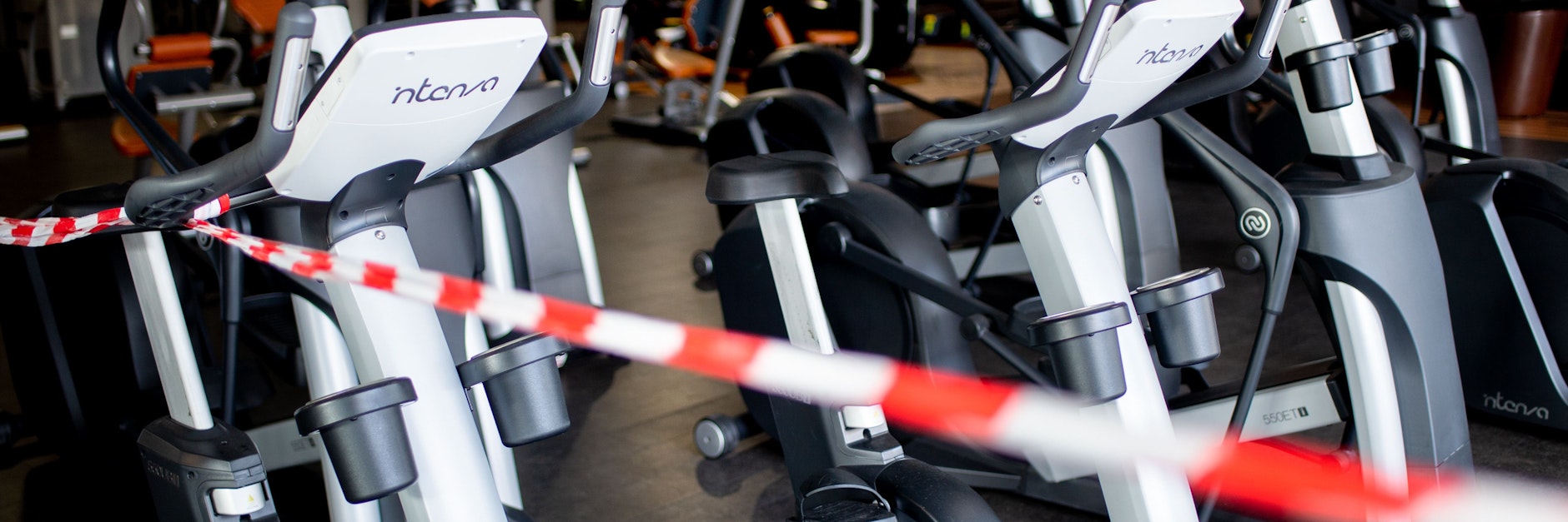 Ein Flatterband sperrt die Fahrradtrainer in einem Fitnessstudio. Wegen des Teil-Lockdown sind die Sportstätten zu.