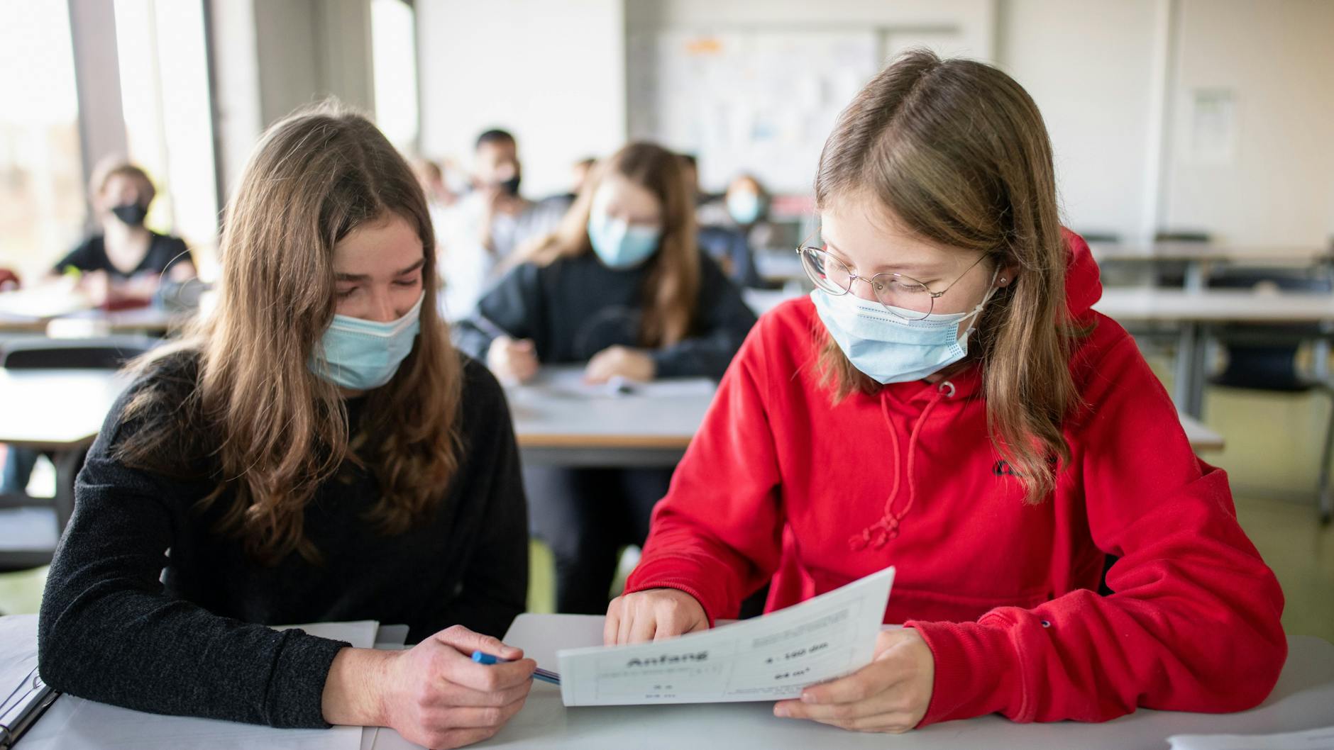 Zwei Schülerinnen im Unterricht. Auch gilt eine Maskenpflicht im Unterricht für alle Schüler der weiterführenden Schulen.