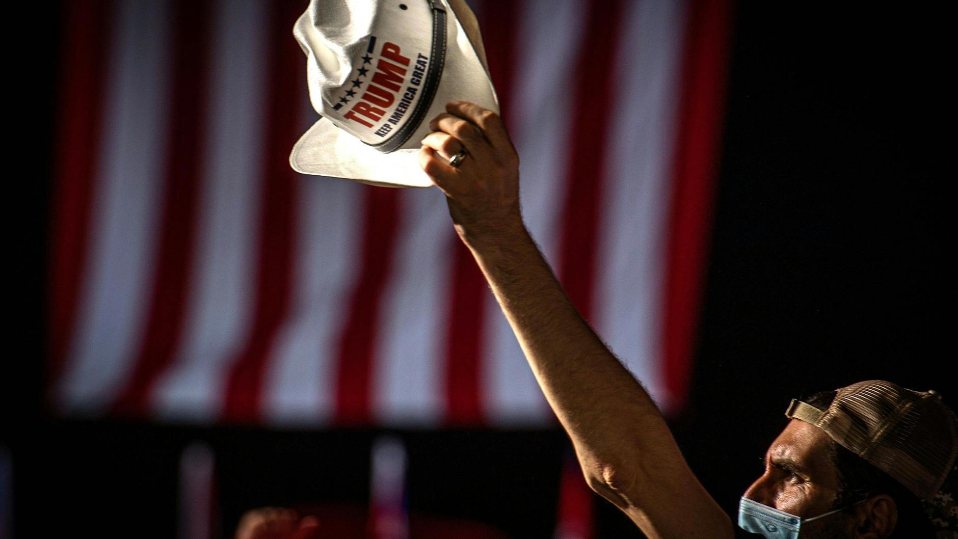 Ein Trump-Anhänger reckt auf einer Wahlkampfveranstaltung seinen Hut in die Höhe. 