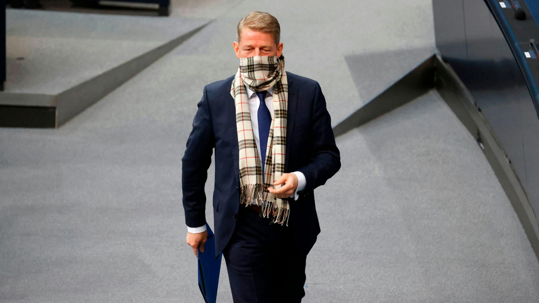Karsten Hilse of the far-right AfD wears a scarf to cover his mouth and nose as he arrives to speak during a debate at the Bundestag on Friday morning.
