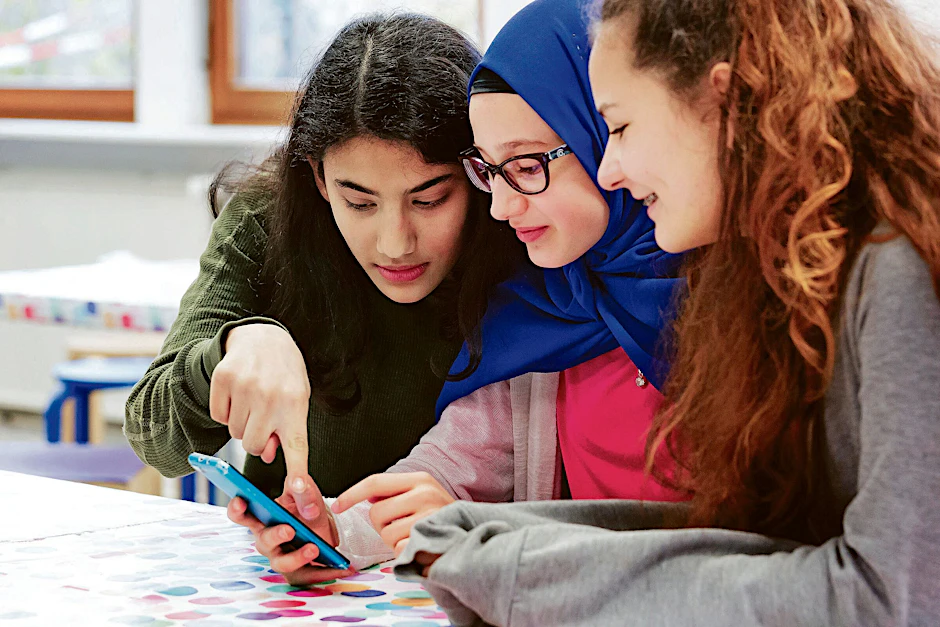 Schülerinnen arbeiten im Klassenraum gemeinsam an einem Instagram-Post.&nbsp;
