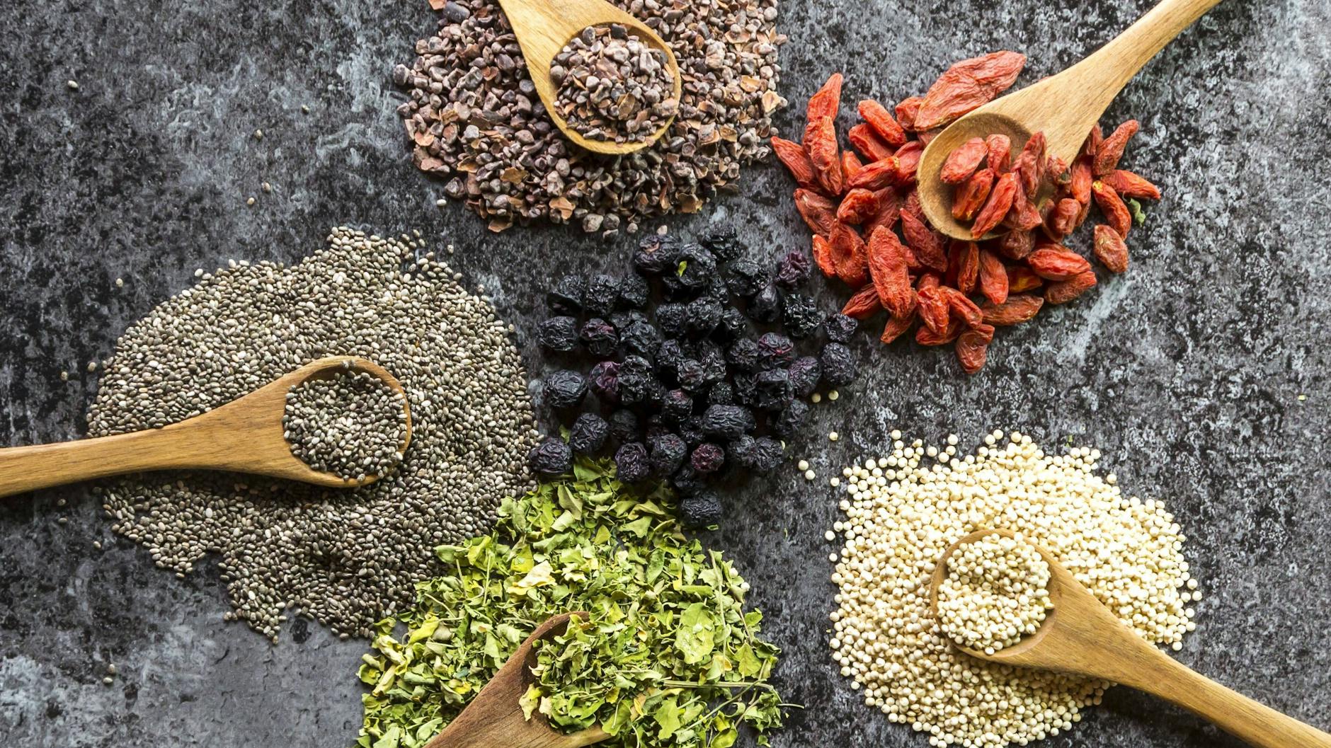 Superfood: Aronia (Bildmitte), Chia (links) und im Uhrzeigersinn Kakao, Goji, Quinoa und Moringa. 