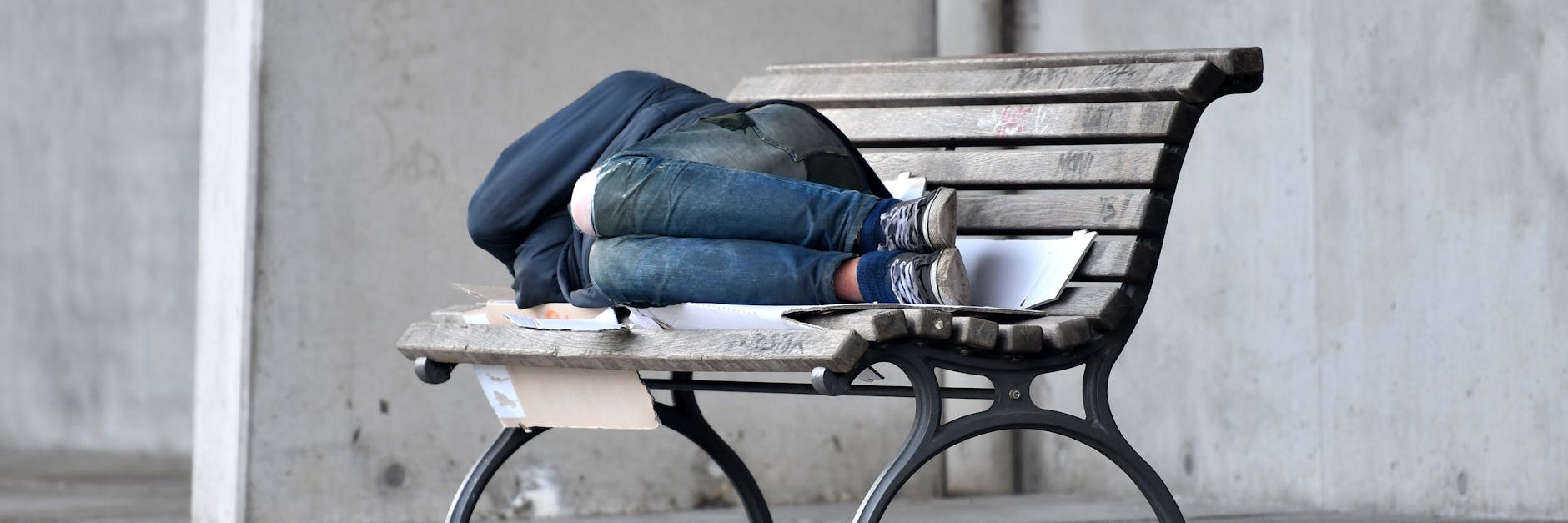 Ein Mann schläf in Berlin auf einer mit Pappkarton ausgelegten Bank im Regierungsviertel. 