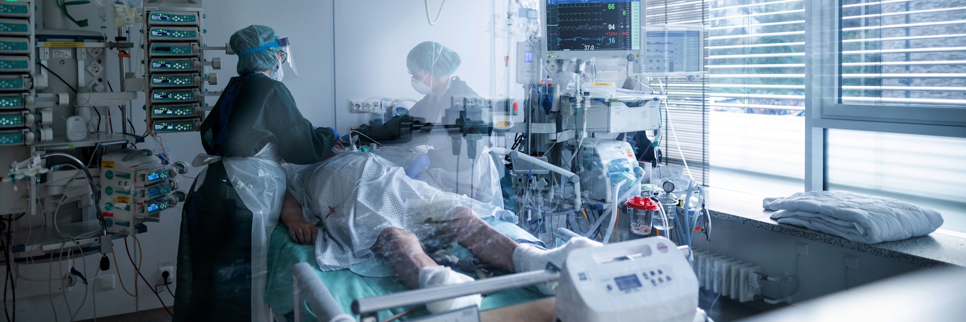 Pflege-Mitarbeiterinnen in Schutzausrüstung betreuen einen Corona-Patienten.