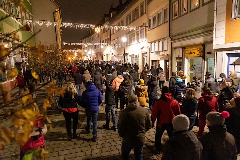 Menschen laufen singend durch die Innenstadt von Hildburghausen und protestieren gegen die neuen Infektionsschutzregeln in dem Kreis.