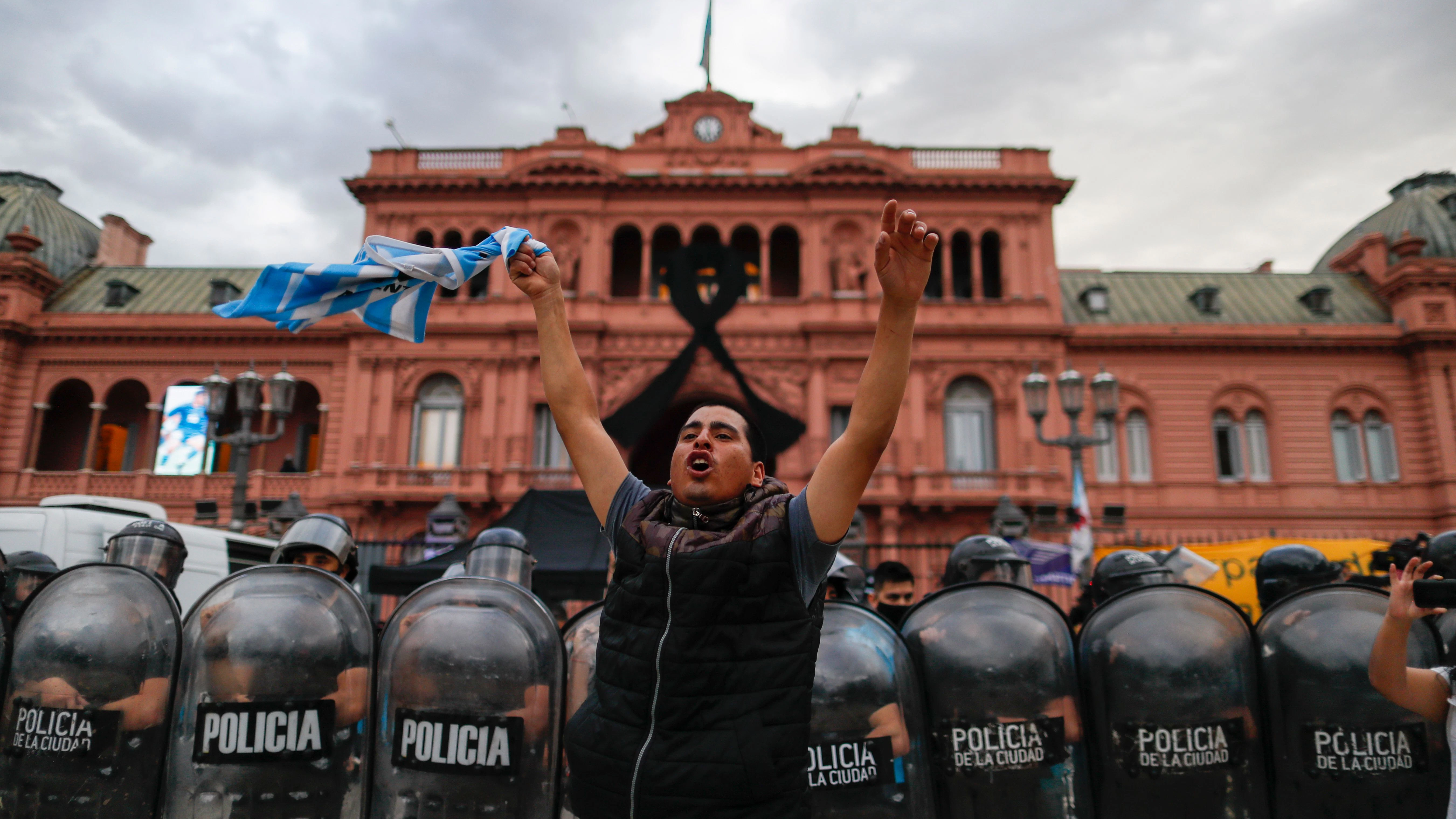 Ein Fußballfan winkt vor dem Präsidentenpalast, während sich die Menschen in einer Schlange vor dem Präsidentenpalast in Buenos Aires aufstellen, um Diego Maradona die letzte Ehre zu erweisen.
