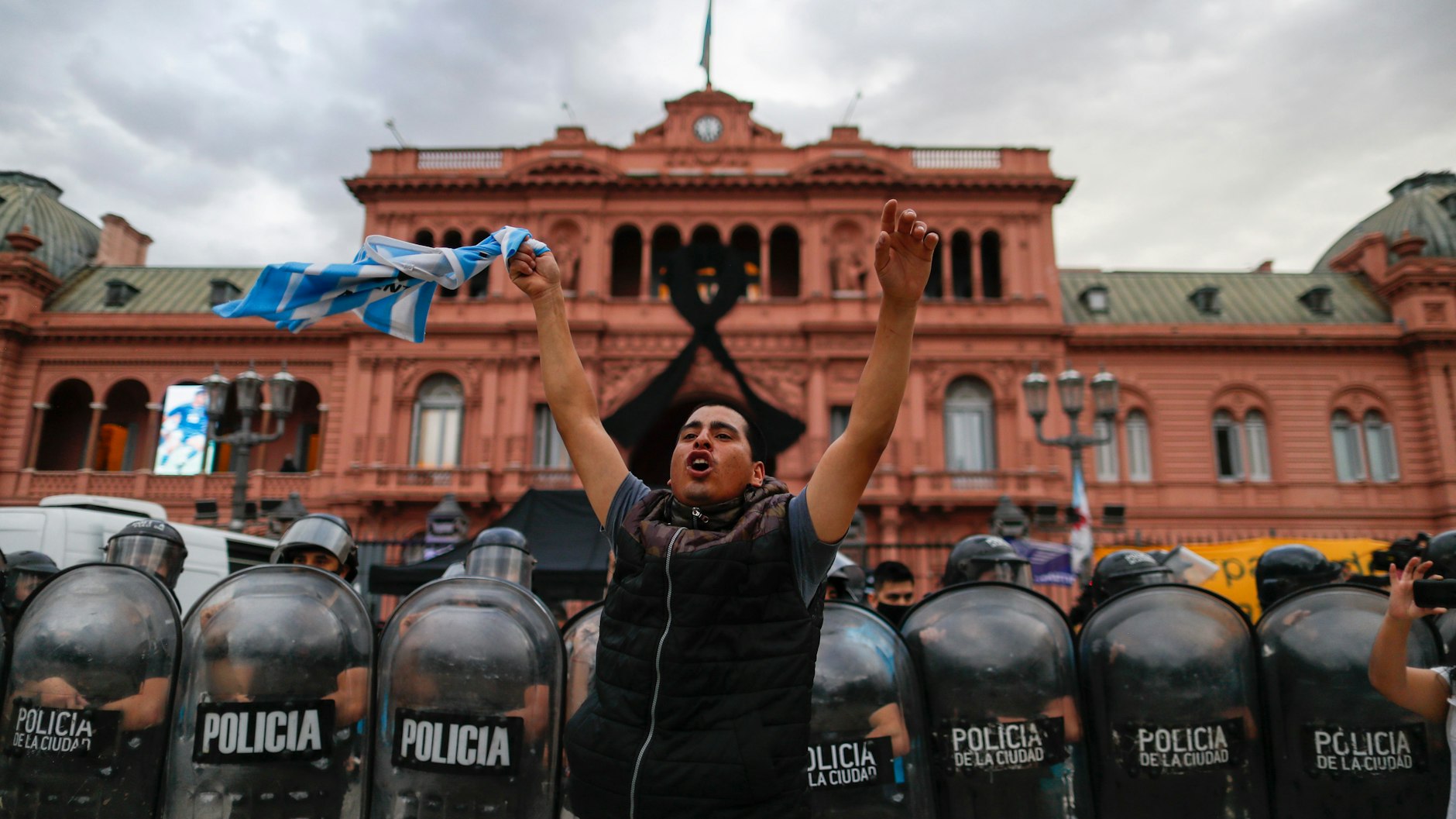 Ein Fußballfan winkt vor dem Präsidentenpalast, während sich die Menschen in einer Schlange vor dem Präsidentenpalast in Buenos Aires aufstellen, um Diego Maradona die letzte Ehre zu erweisen.