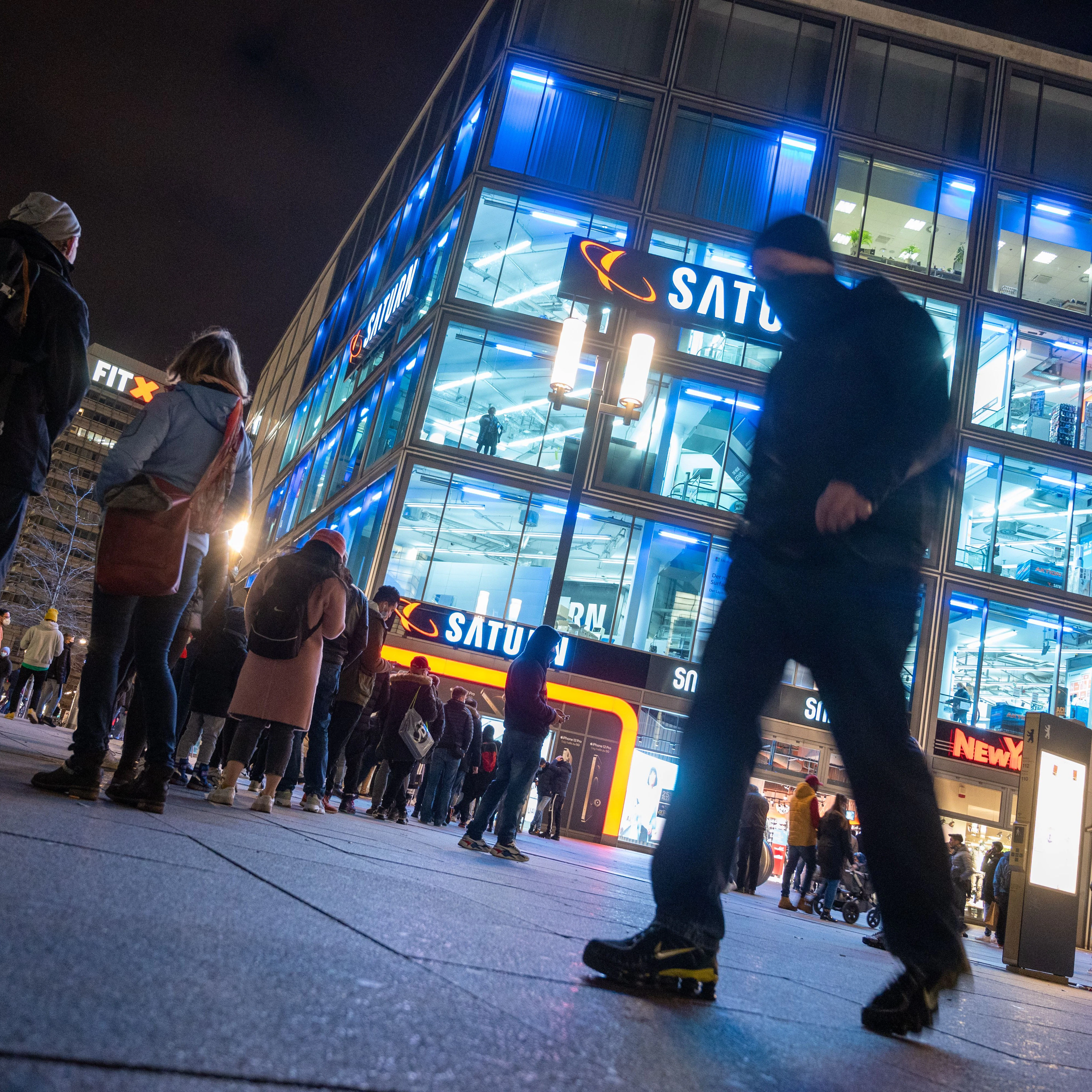 Vor dem Elektronikmarkt Saturn am Alexanderplatz warten Menschen in einer Warteschlange. Die Einzelhändler müssen verschärfte Corona-Auflagen umsetzen.&nbsp;