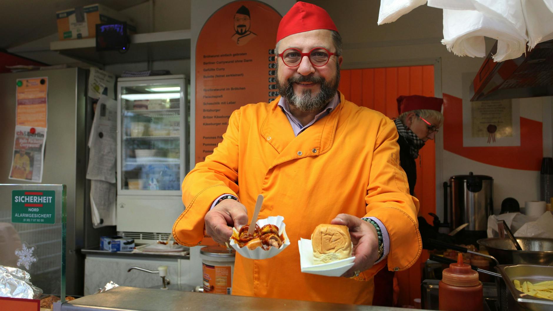 Andreas Kämpf alias „Curry-Paule“ reicht eine Currywurst über den Tresen. 
