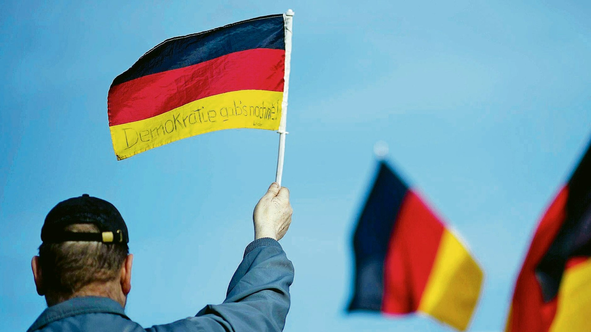 „Demokratie gab's noch nie“ steht auf der Fahne. Der Demonstrant schwenkt sie bei einem&nbsp; Aufzug rechter Gruppen wie Baergida und Pediga in Berlin 2017 gegen die Einwanderungspolitik der Kanzlerin.&nbsp;<br>