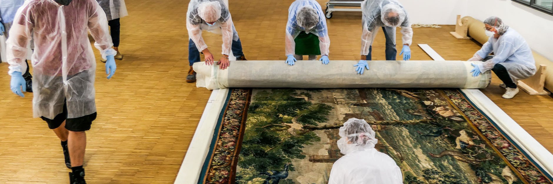 Mitarbeiter des Bayerischen Nationalmuseums rollen eine Tapisserie zusammen und verpacken sie vor der Übergabe an die Beauftragten der Erbengemeinschaft.